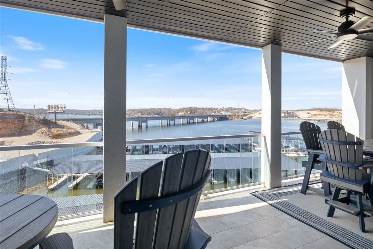 A tranquil outdoor seating area overlooks the sparkling lake, with nearby docks visible in the background. The view suggests easy access to water activities and a relaxing spot to watch the action or unwind after a day on the lake.