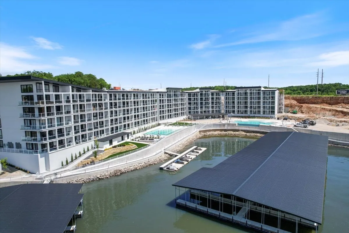 This image showcases the modern architecture of the building, vibrant swimming pools, and, crucially, boats docked in the marina alongside the waterfront. The scene is lively and inviting, evoking the excitement of water-based activities and the convenience of having direct access to boating amenities.
