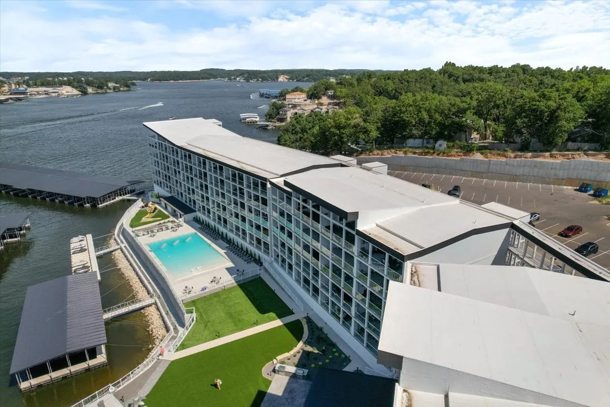 This exterior image captures a sparkling swimming pool overlooking the lake, with a green lawn and the building's modern facade in the background. The inviting poolside area is perfect for social gatherings or unwinding after a day out, while the waterfront provides a serene backdrop for sunset views and water activities.