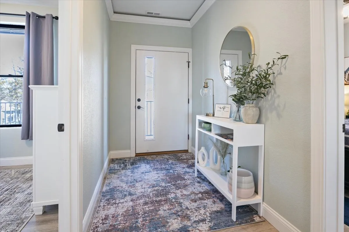 A view of the front door area, featuring a sleek console table, decorative mirror, and a stylish rug. The entryway is clean and inviting, suggesting attention to detail and security for guests.
