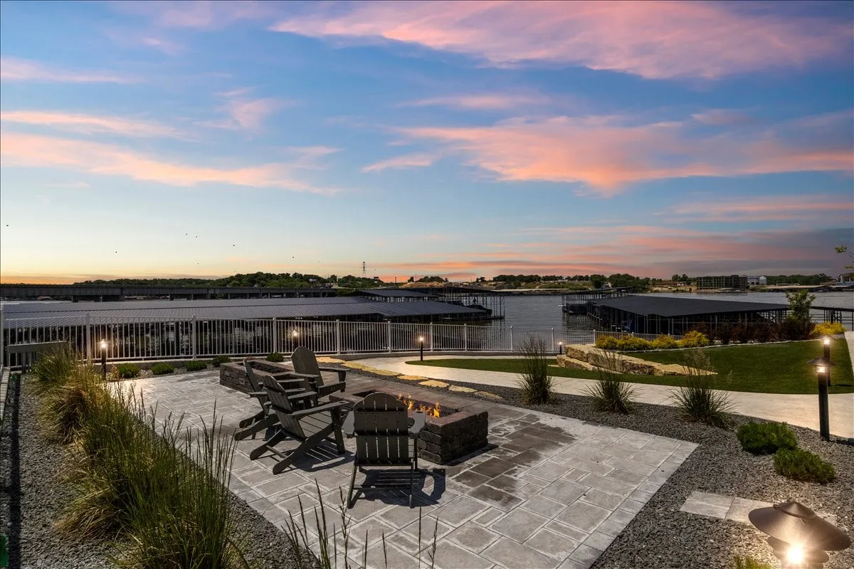 An inviting fire pit area with Adirondack chairs overlooking the tranquil water, surrounded by tasteful landscaping. The scene exudes a peaceful, communal vibe that's perfect for gathering at sunset or enjoying stargazing nights by the water.