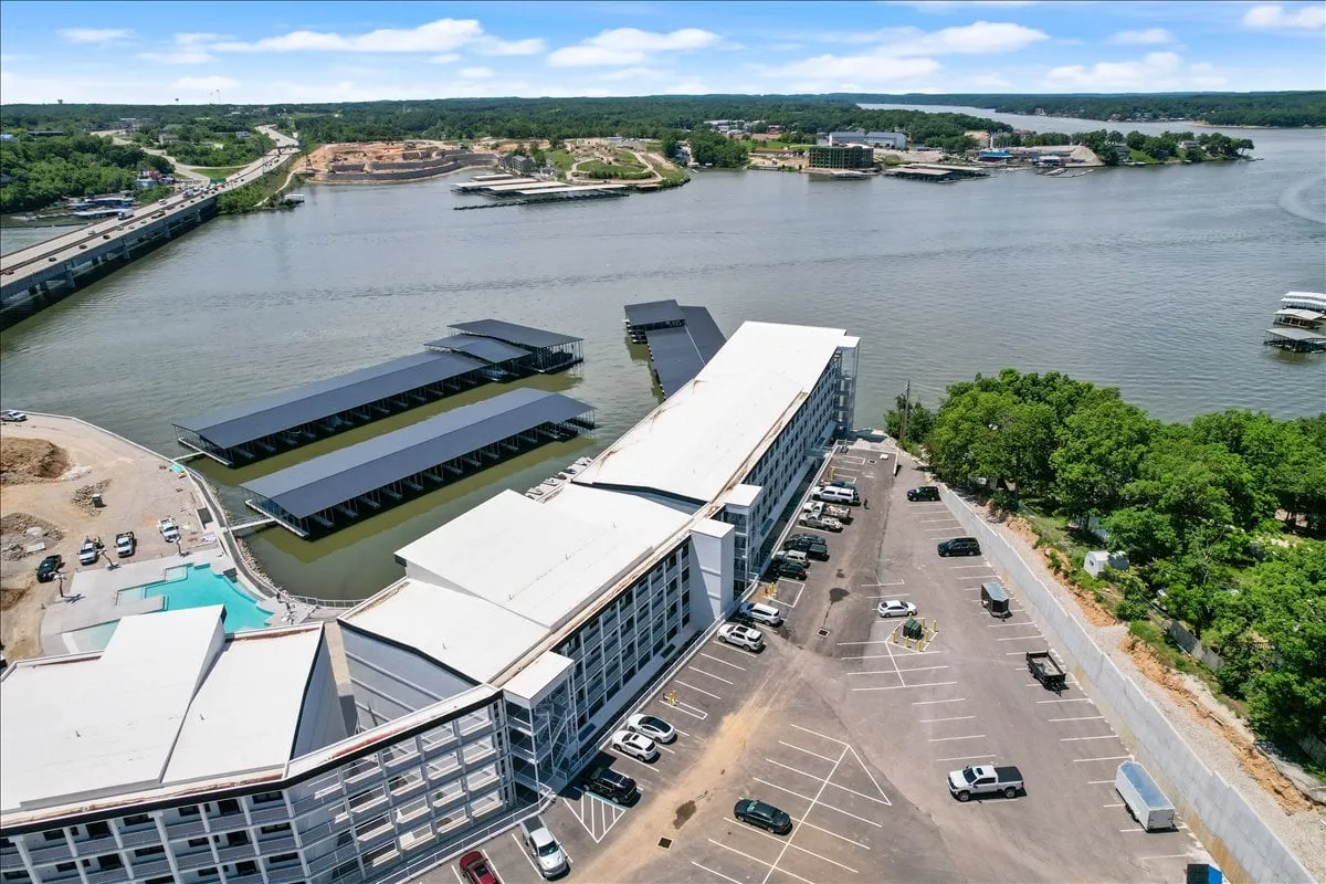 This exterior view focuses on the lakefront and the private boat docks extending into the water, with a tranquil hotel structure in the background. Boats are visible at the docks, emphasizing the property’s direct water access and boating amenities.